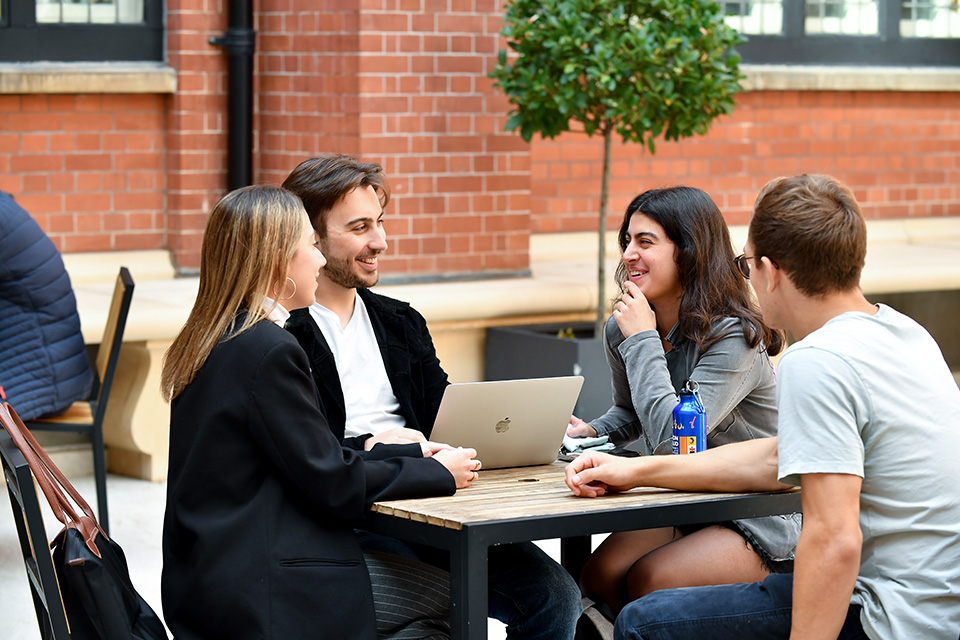 Students sitting down and chatting in a red-brick courtyard